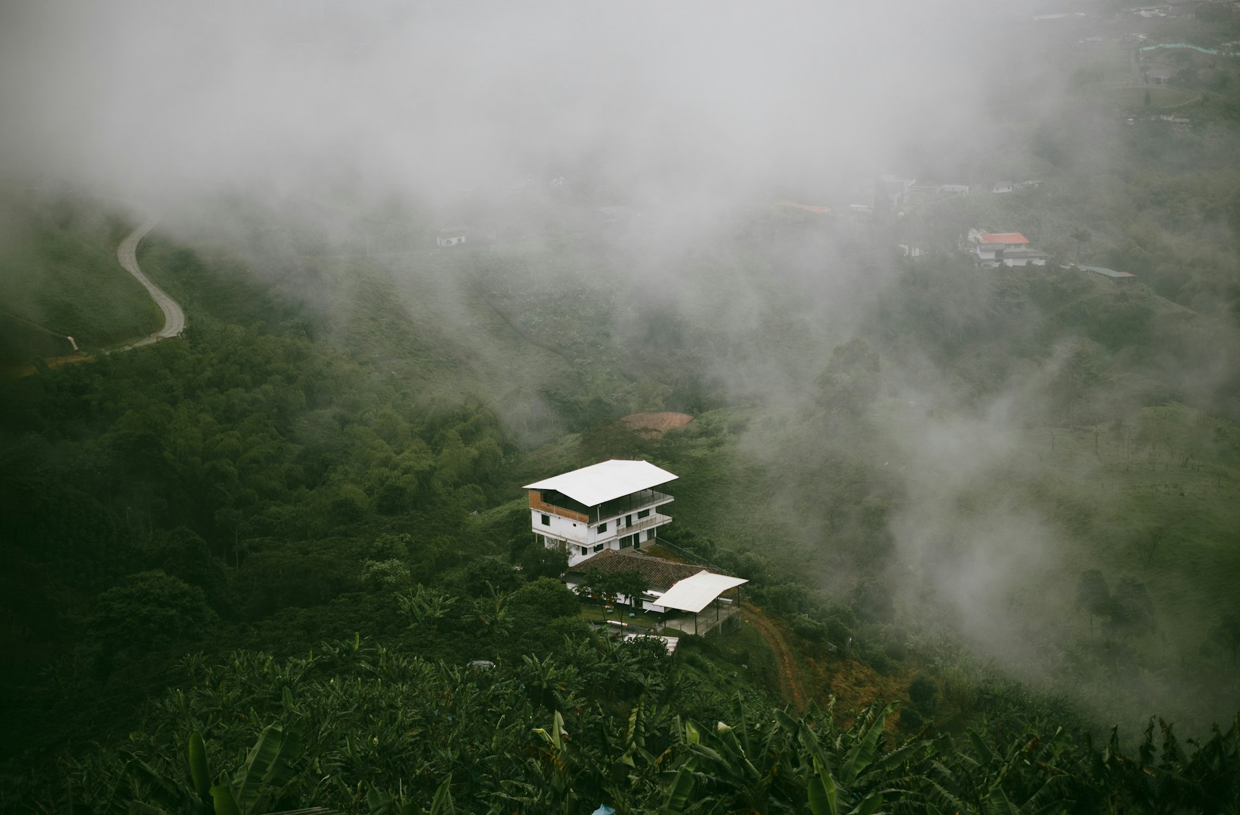 Casas brancas na montanha verde, envoltas pela neblina